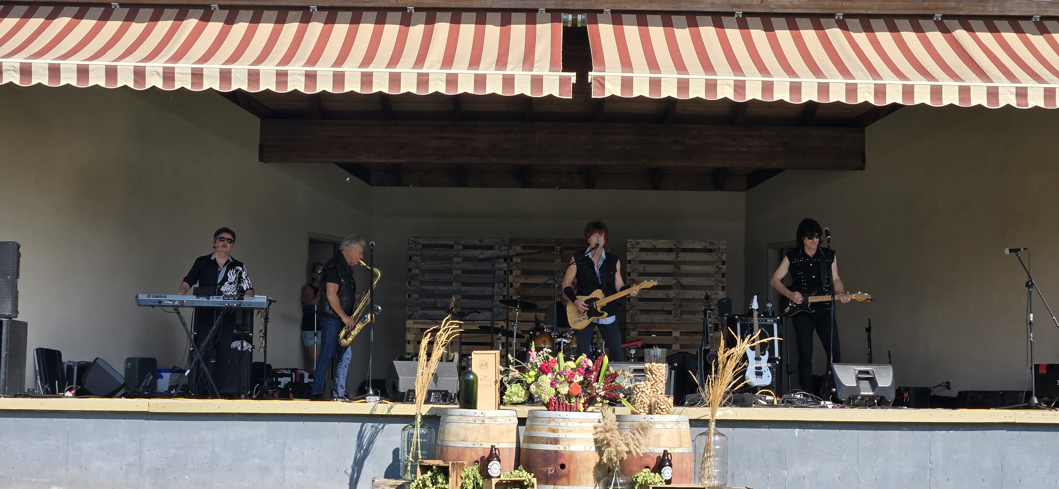 Classic rock tribute performance on an outdoor stage decorated with wine barrels